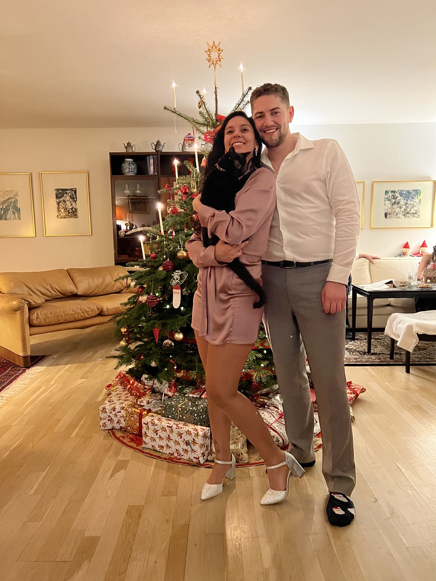 Patricia holding Ema the cat, with Sebastian, by the Christmas tree